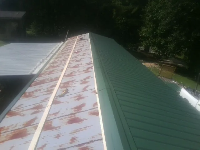 Old rusted panels beside newly installed green metal roofing — Wind Damage Roof Repair by Roofing Brothers in Myrtle
