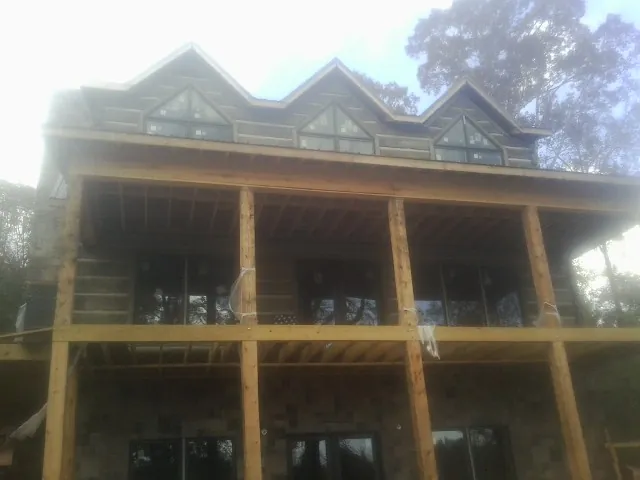 Dormers and porch framing on a large log home under construction — Roof Coating work by our crew in Myrtle