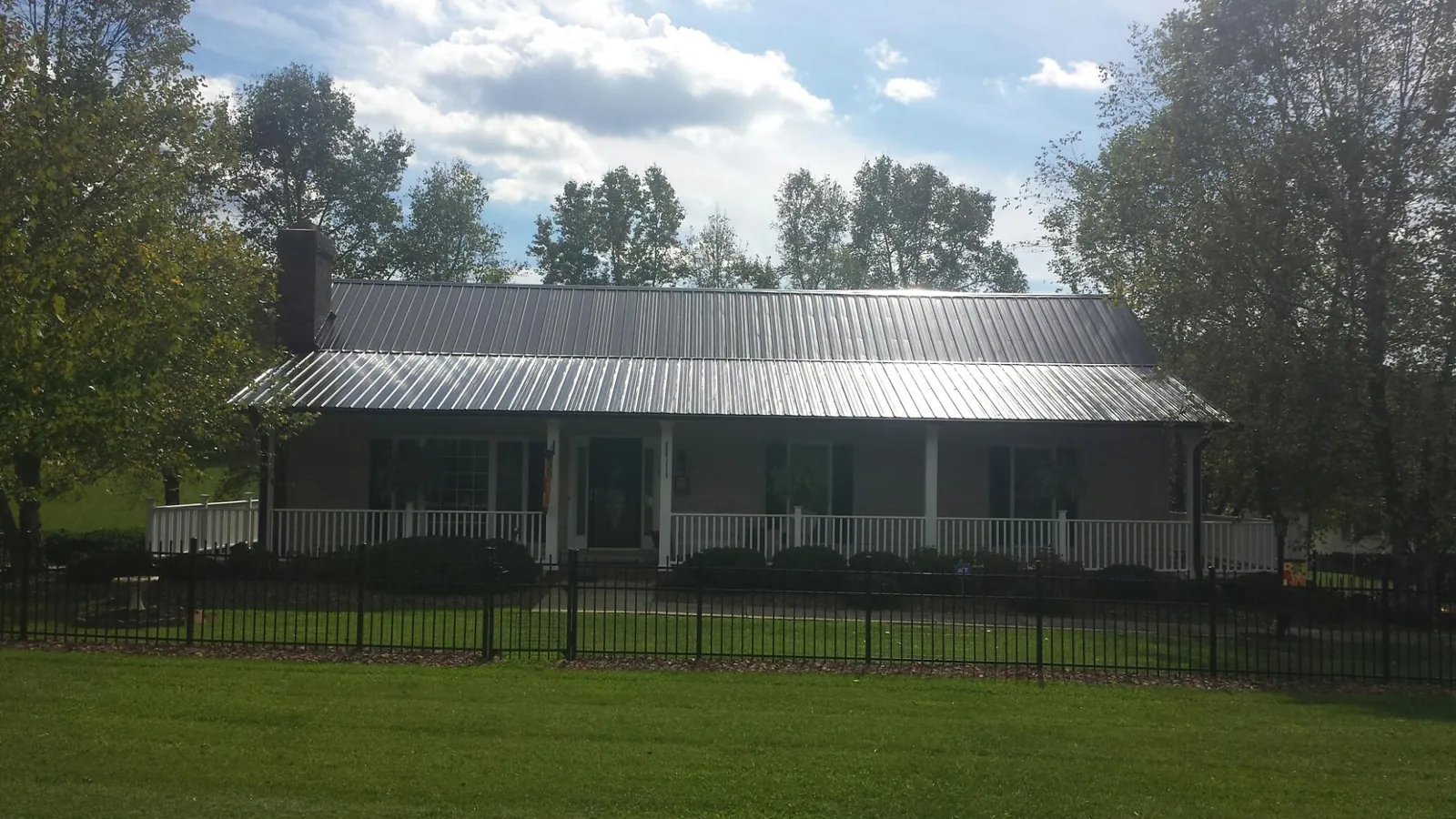 Gray metal roof on a brick ranch with a full width front porch — Gutter Guard Installation work by our crew in Myrtle