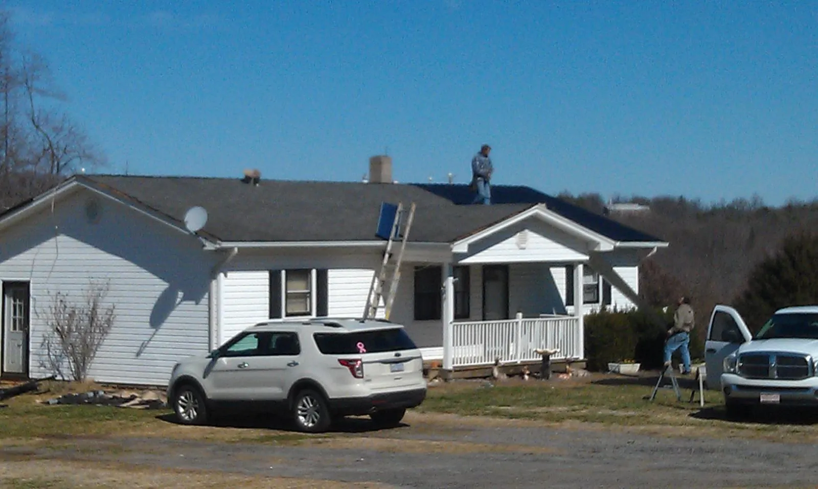 Roofers stripping shingles from a white ranch house roof in Myrtle